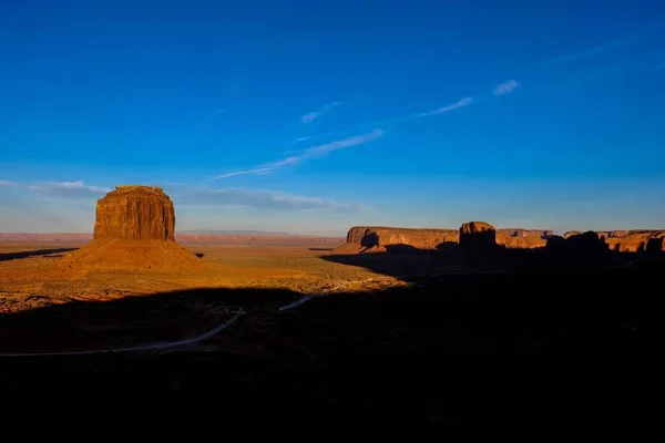Luchtfoto van weg n midden in de woestijn met een grote klif in de verte onder een blauwe lucht — Stockfoto
