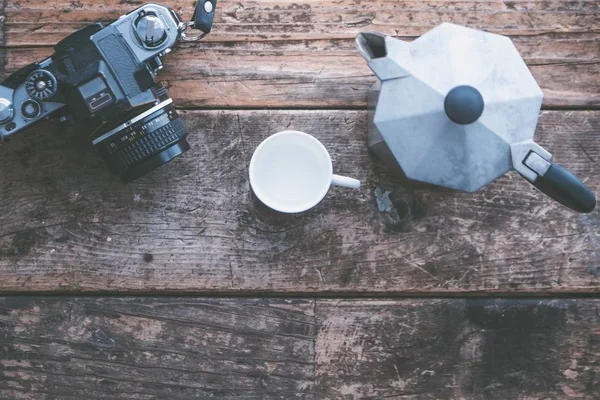 Fotografia aérea de uma câmera profissional com uma caneca branca e um bule de chá cinza em um fundo de madeira — Fotografia de Stock