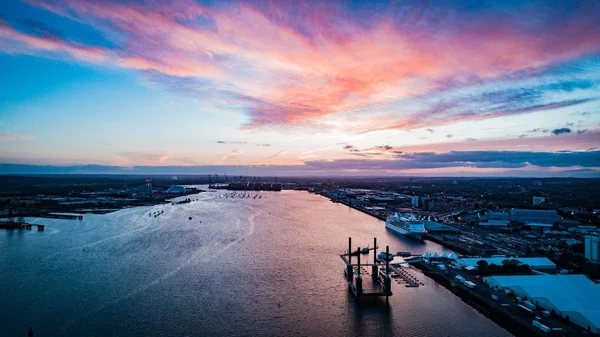 Wide distant shot of boats floating on the body of water in the city under a pinkish sky — Stock Photo, Image