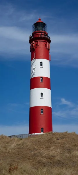 Vacker vertikal bild av en röd och vit randig fyrtorn vid stranden — Stockfoto