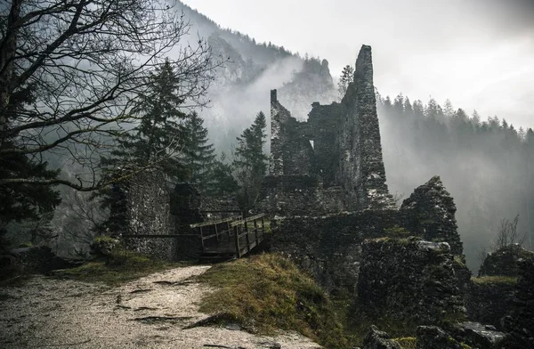 A destroyed stone structure in the foggy woods with a bridge — Stock Photo, Image