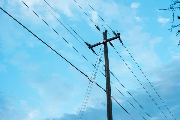 Baixo ângulo tiro de um poste de eletricidade de madeira com fios grossos em um azul belo céu fundo azul — Fotografia de Stock
