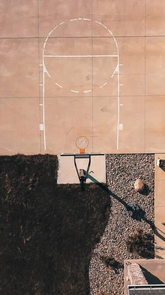 Colpo in testa di un campo da basket in cemento con il cerchio e rocce — Foto Stock