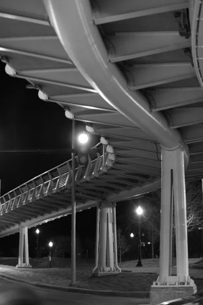 Tiro vertical a escala de grises de un puente metálico disparado por la noche — Foto de Stock