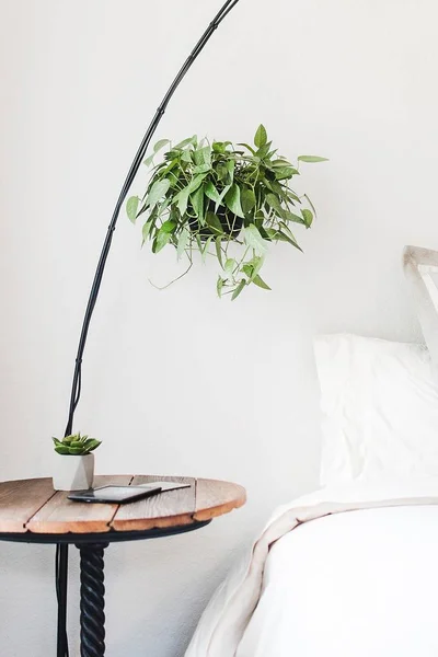 Vertical shot of a round brown side table beside a bed — Stock Photo, Image