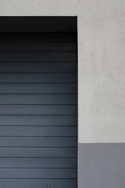 Lato di una porta garage in metallo su una parete bianca e grigia — Foto Stock