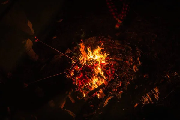 Οι άνθρωποι στέκονται γύρω από τη φωτιά κρατώντας μπαστούνια και προθέρμανση τη νύχτα — Φωτογραφία Αρχείου