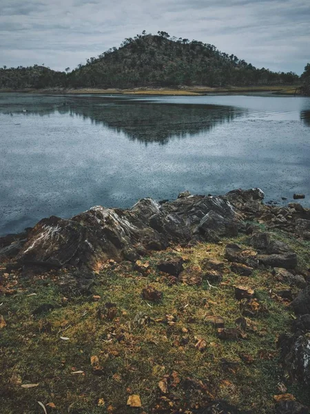 Arka planda dağ refecting su yakınındaki kayaların dikey çekim — Stok fotoğraf