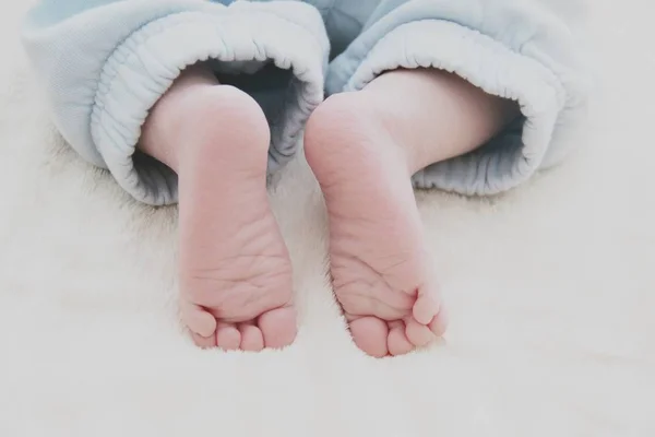 Крупный план ног ребенка на белом одеяле — стоковое фото