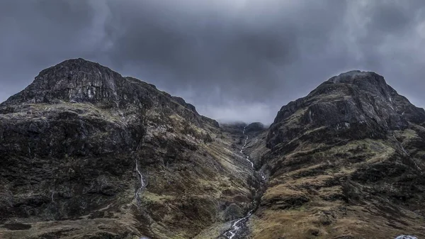 昼間の灰色の嵐の空の下で岩の高い山々の美しい低角度ショット — ストック写真