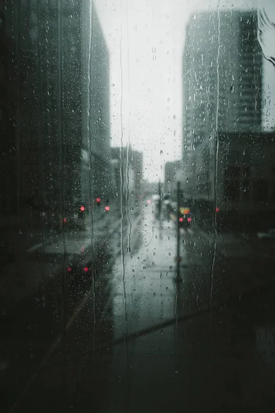 Вертикальный снимок дождевых капель, стекающих по стеклу — стоковое фото