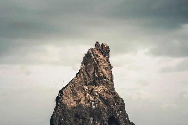 Tiro largo de uma rocha alta abaixo de um céu claro — Fotografia de Stock