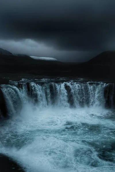 Una bella cascata in un campo con cielo scuro — Foto Stock