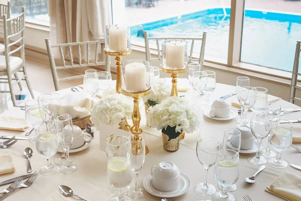 Shot van witte pilaar kaarsen in candelabra en witte bloemen boeketten op een bruiloft tafel — Stockfoto