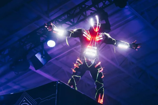Männlicher Interpret in einem weiß-roten LED-Anzug, der auf einem hohen Podest bei einem DJ-Konzert steht — Stockfoto