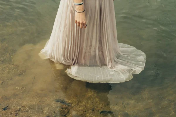 Female wearing a long gown dress standing in the water — Stock Photo, Image