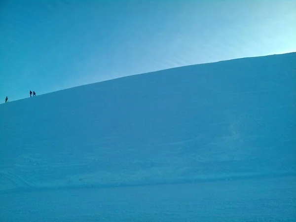 Weitwinkelaufnahme von ein paar Menschen, die einen Hügel unter einem klaren blauen Himmel hinuntergehen — Stockfoto