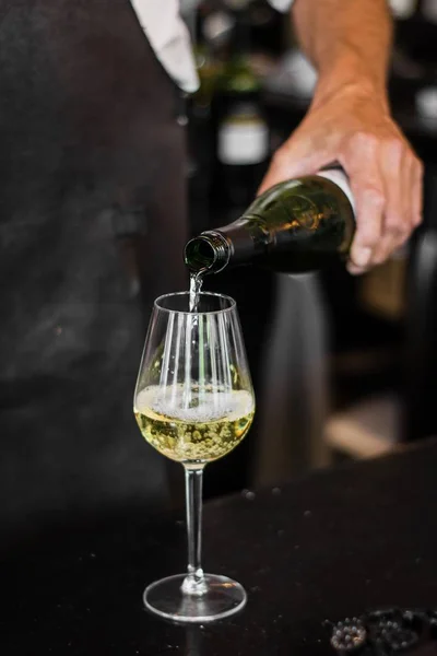 Pionowy strzał barmana nalewanie wina w szklance z niewyraźne tło — Zdjęcie stockowe