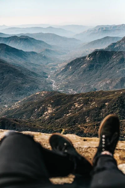 Nohy člověka na poli s úžasným výhledem na hory a kopce v dálce — Stock fotografie