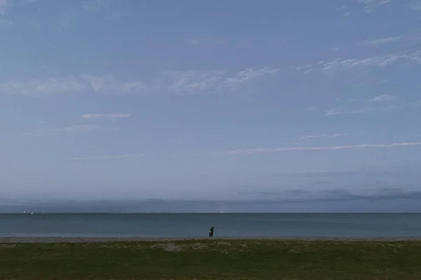 Ampio colpo di mare vicino a campo di erba piatta sotto un cielo blu chiaro — Foto Stock