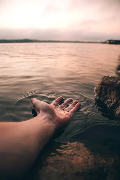 Vertikal närbild skott av en person med sin hand i vatten — Stockfoto