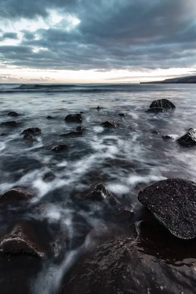 Прекрасний знімок скелястого узбережжя моря з дивовижною водною текстурою і захоплюючим хмарним сірим небом — стокове фото