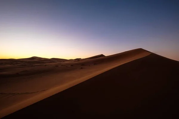 Prachtige opname van zandduinen onder een paarse en blauwe lucht — Stockfoto