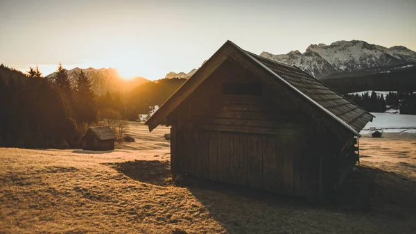Shot egy kis faház, száraz fű körül, amikor naplementekor a hegyek backgro — Stock Fotó