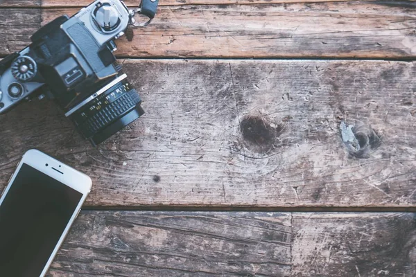 Fotografia aérea de uma câmera e um smartphone em um fundo de madeira marrom — Fotografia de Stock