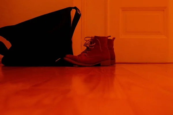 Wide shot of red boots on the floor near a black bag