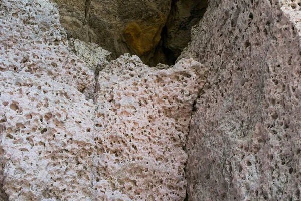 Lichtroze kalksteen, met verweervings- en erosiegaten, gevonden op een rotswand in Malta. — Stockfoto