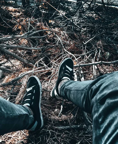 Pieds de personne en jeans et baskets noires sur brindilles dans une forêt — Photo