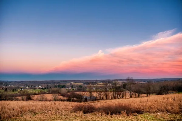 Belo campo seco com nuvens rosa e roxas acima ao pôr-do-sol — Fotografia de Stock