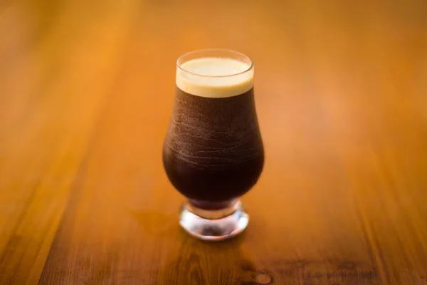 Ein kaltes Glas dunkles Bier auf einer Holzoberfläche — Stockfoto