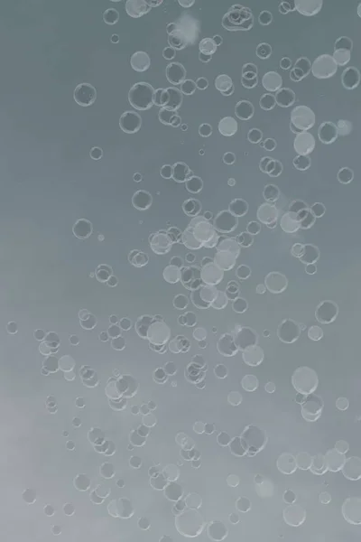 Vertikale Aufnahme von Seifenblasen auf hellgrauem Hintergrund — Stockfoto