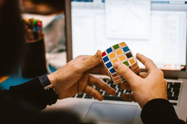 Closeup shot of a male solving a colorful 4x4 rubic cube — Stock Photo, Image