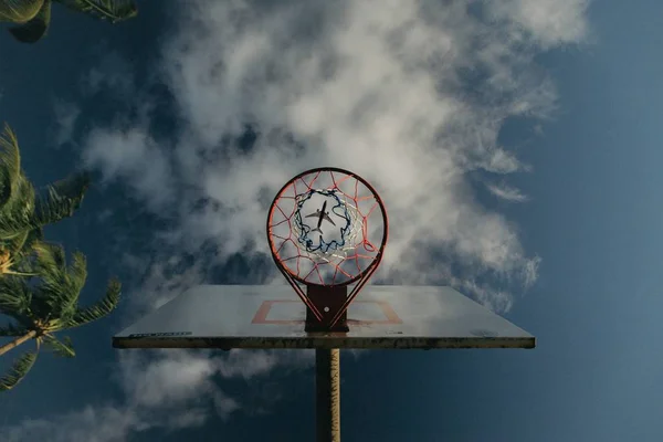 Ujęcie obręczy do koszykówki z samolotem widocznym przez dziurę w koszu na niebie — Zdjęcie stockowe