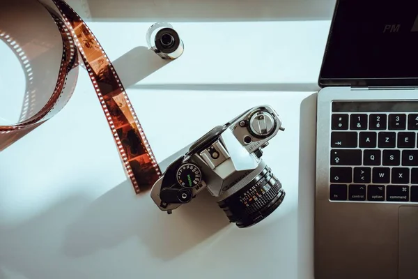 Câmera profissional com um filme real ao lado de um laptop — Fotografia de Stock