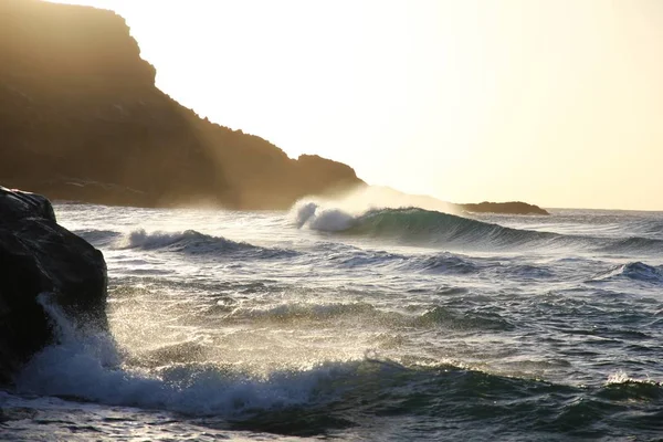 Piękny Strzał Fal Morskich Uderzając Skały Pobliżu Góry Jasnym Niebie — Zdjęcie stockowe