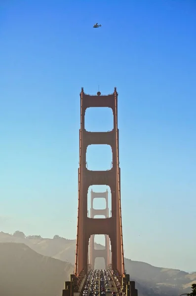 Belo tiro vertical de uma ponte movimentada com muito tráfego e um avião voando por cima — Fotografia de Stock