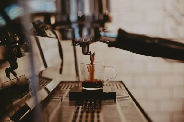 Closeup a fém kávéfőző gép öntés kávét egy pohár pohárba — Stock Fotó