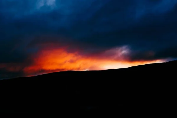 Silhueta de uma colina com nuvens incríveis e o sol durante a hora de ouro no fundo — Fotografia de Stock