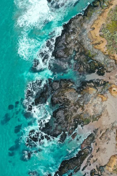 Vertical overhead shot of the beautiful shoreline of the sea with blue clean water and sandy beach — Stock Photo, Image