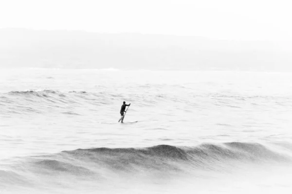 Foto en blanco y negro de una persona en medio del mar —  Fotos de Stock