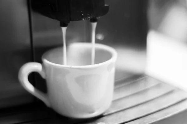 Macchina da caffè versando il caffè in una tazza di caffè bianco girato in bianco e nero — Foto Stock