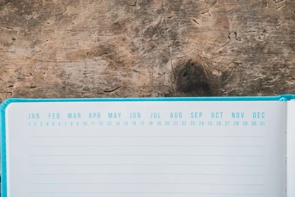 Libro de texto azul abierto con marcadores de fecha en la parte superior sobre una superficie de madera — Foto de Stock