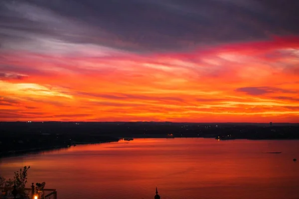 Belo tiro de um lago com um incrível céu nublado vermelho de tirar o fôlego durante o pôr do sol — Fotografia de Stock