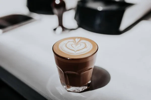 Close-up van een prachtig gemaakte cappuccino in een glazen beker op een witte tafel — Stockfoto