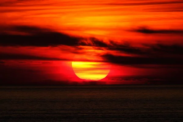 Schöne Aufnahme eines Meeres und der Sonne hinter den Wolken bei Sonnenuntergang — Stockfoto