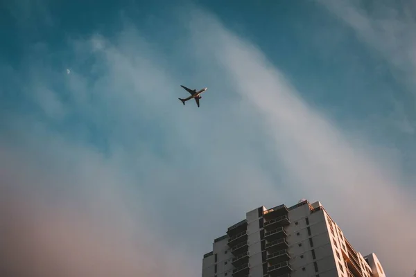 曇り空を通って建物の上空を飛ぶ飛行機 — ストック写真